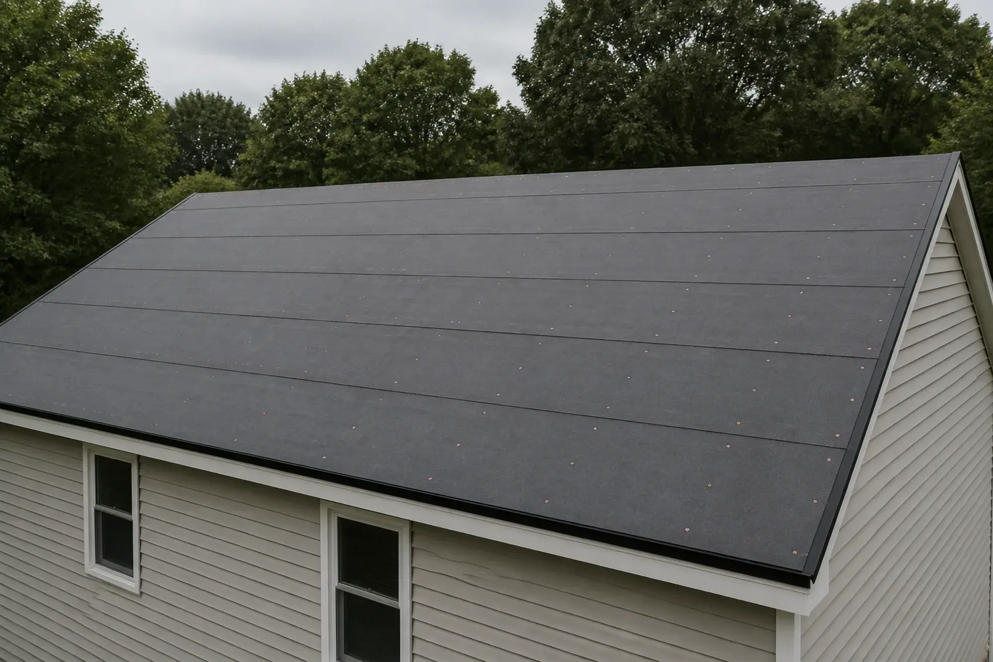 A gabled roof covered in continuous underlayment before shingle installation.