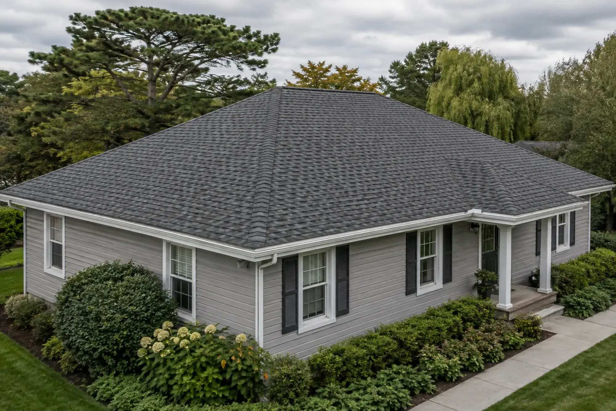A completed grey shingle hip roof with aligned courses and clean white gutters.