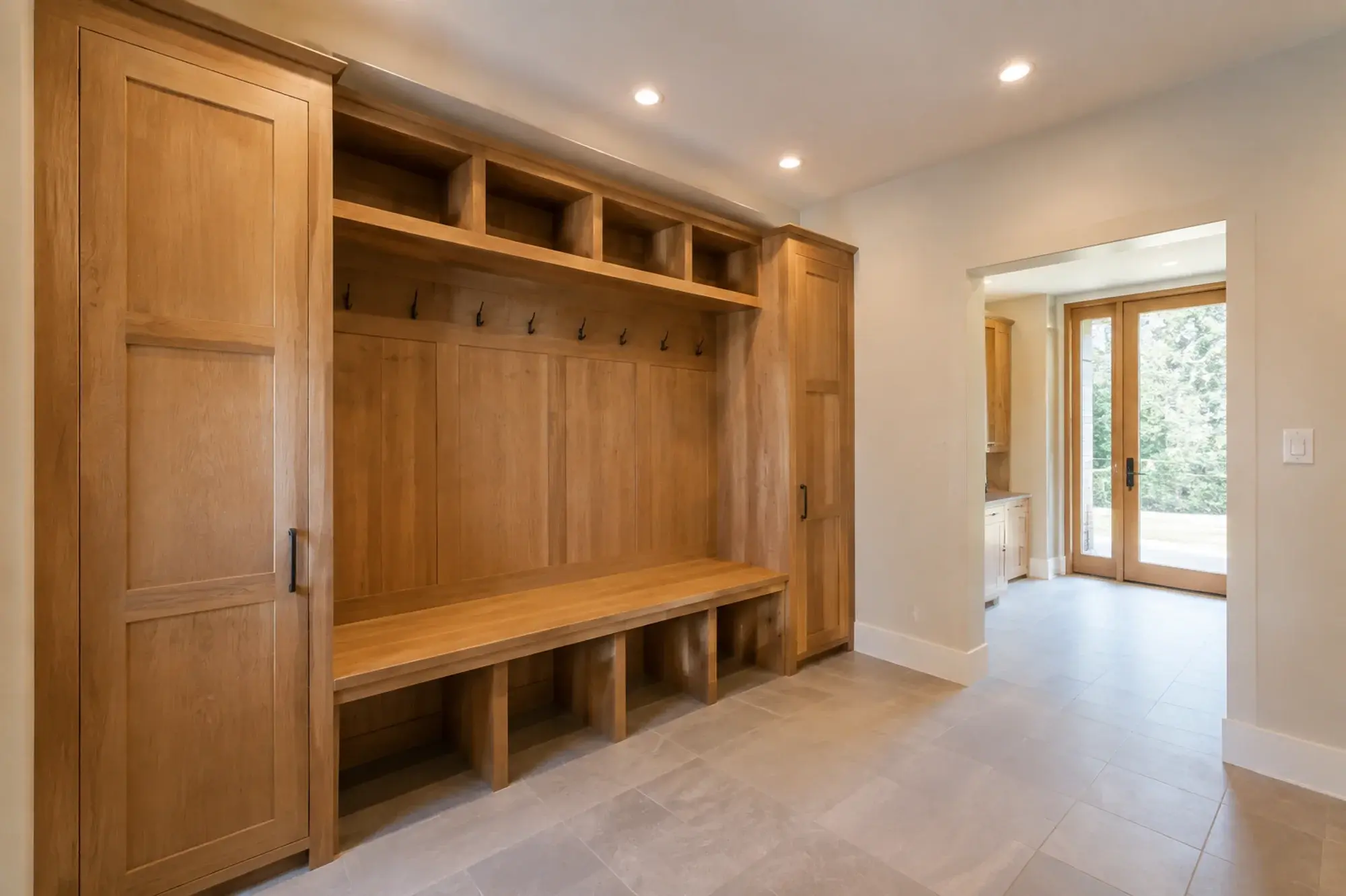 Mudroom concept with warm recessed lighting above an oak bench.